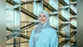 Portrait picture, smiling, blue Abaya, blue-brown gradient Hijab, and brown background with metal beems